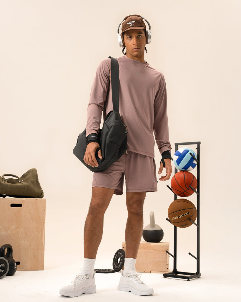 Man stretching in dusty rose performance top for gym warm-up